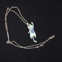 В таинственных землях Эльдариона, где магия сплетается с реальностью, был создан этот волшебный кулон в виде игривого кота. Словно сотканный из лунного света и осколков звёздного неба, он покоится на изящной серебряной цепочке, которая переливается, будто сотканная из нитей древней магии. Кот на подвеске — не просто украшение, а хранитель маленьких секретов. Его полупрозрачная фигура, созданная из эпоксидной смолы, словно застыла в прыжке, а на шерсти мерцает узор, напоминающий лепестки зачарованного цветка. Говорят, что этот узор способен менять оттенки в зависимости от настроения владельца: становится нежно-голубым, когда сердце наполнено радостью, или глубоким фиолетовым, если душа тоскует. Легенда гласит, что этот кот — дух-хранитель, призванный оберегать своего владельца от бед и невзгод. В полнолуние он оживает на мгновение, чтобы прошептать на ухо своему хозяину древние истины или предупредить о грядущей опасности. Его хвост — это нить судьбы, связывающая владельца с магией мира, а глаза хранят в себе силу видеть то, что скрыто от обычного взгляда. Этот кулон — не просто аксессуар, а талисман, который принесёт удачу, защитит от злых чар и подарит своему владельцу частичку волшебства Эльдариона. Носите его с гордостью, и пусть магия сопровождает вас во всех приключениях!