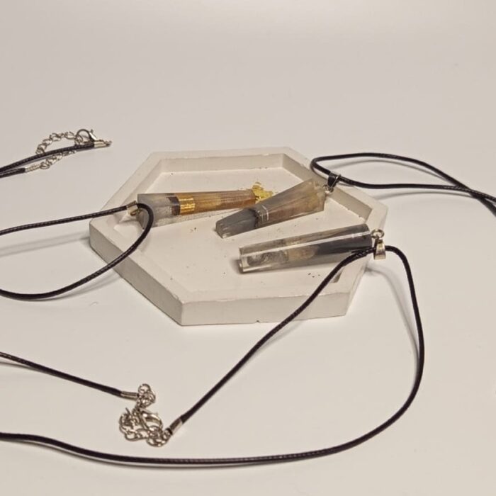 Кулон с окурком: загадочный аксессуар с характером Представляем вам необычный кулон, который сочетает в себе минимализм и дерзкий шарм. Изделие выполнено в виде удлинённого прозрачного кристалла, внутри которого заключён миниатюрный окурок — словно застывший фрагмент повседневности, превращённый в произведение искусства. Особенности кулона: * Материал: прозрачная смола или акрил, надёжно сохраняющая «секрет» внутри. * Дизайн: лаконичная форма с заострённым концом придаёт украшению современный вид. * Шнурок: прочный чёрный шнур с металлической застёжкой — универсальный вариант, который подойдёт к любой одежде. * Размер: компактный, не отвлекает от образа, но при этом заметен при ближайшем рассмотрении. Почему этот кулон стоит внимания? * Уникальный дизайн. Такой аксессуар точно выделит вас из толпы и станет поводом для интересных бесед. * Символика. Окурок в кулоне может восприниматься как ироничный символ свободы, непринуждённости или даже философии «живи настоящим моментом». * Универсальность. Подходит как мужчинам, так и женщинам — идеален для поклонников альтернативной моды, рок-стиля или кэжуал-образов. * Лёгкость в уходе. Прозрачный материал легко очищается, а шнур устойчив к износу. Этот кулон — не просто украшение, а смелое заявление о вашем чувстве юмора и индивидуальности. Носите его с джинсами и футболкой, кожаной курткой или даже с классическим пальто — он добавит образу изюминку и характер.