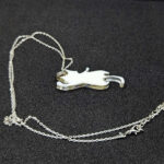 В таинственных землях Эльдариона, где магия сплетается с реальностью, был создан этот волшебный кулон в виде игривого кота. Словно сотканный из лунного света и осколков звёздного неба, он покоится на изящной серебряной цепочке, которая переливается, будто сотканная из нитей древней магии. Кот на подвеске — не просто украшение, а хранитель маленьких секретов. Его полупрозрачная фигура, созданная из эпоксидной смолы, словно застыла в прыжке, а на шерсти мерцает узор, напоминающий лепестки зачарованного цветка. Говорят, что этот узор способен менять оттенки в зависимости от настроения владельца: становится нежно-голубым, когда сердце наполнено радостью, или глубоким фиолетовым, если душа тоскует. Легенда гласит, что этот кот — дух-хранитель, призванный оберегать своего владельца от бед и невзгод. В полнолуние он оживает на мгновение, чтобы прошептать на ухо своему хозяину древние истины или предупредить о грядущей опасности. Его хвост — это нить судьбы, связывающая владельца с магией мира, а глаза хранят в себе силу видеть то, что скрыто от обычного взгляда. Этот кулон — не просто аксессуар, а талисман, который принесёт удачу, защитит от злых чар и подарит своему владельцу частичку волшебства Эльдариона. Носите его с гордостью, и пусть магия сопровождает вас во всех приключениях!