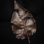 Миниатюрная брошь в виде листа сирени, выполненная с помощью удивительной техники гальванопластика. Лист словно оживает в металле, храня в себе память о тёплом летнем вечере и лёгком аромате цветущего сада.