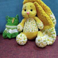 Представляем очаровательную вязаную зайку, выполненную из мягкой плюшевой пряжи. Игрушка выглядит очень уютно и привлекательно — идеальный вариант для подарка ребёнку или украшения интерьера. Материал: плюшевая пряжа, приятная на ощупь, гиппоаллергенная. Цвет: основной цвет игрушки — солнечно-жёлтый с вкраплениями белого и светло-зелёного, создающими эффект «цветочного» узора. Дизайн: длинные мягкие ушки, придающие зайке особый шарм; Выразительные глазки на безопасном креплении; милый розовый носик; аккуратные лапки и туловище с объёмной текстурой. Комплектация: сама зайка; вязаное платье зелёного цвета с белым; Платье украшено декоративной брошкой в виде зайчика, что добавляет изделию индивидуальности. Инструкция-рекомендация по уходу. Подарочная упаковка(на Ваш выбор,по согласованию). Размер: компактный, удобно держать в руках (точный размер зависит от конкретной вязки,толщины и метража нити). Безопасность: Глаза и носик на безопасном креплении,с дополнительной фиксацией(запаяны).Лапки и ушки ввязаны в изделие.Игрушка безопасна для детей. Преимущества: ручная работа — каждая игрушка уникальна;экологичные и безопасные материалы;универсальность: подойдёт как для игр, так и для коллекционирования.Эта зайка станет любимым другом ребёнка или милым сувениром для близких. Подарите тепло и уют с этой очаровательной игрушкой. Возможно изготовление под Ваши пожелания в другом цвете,комплектации аксессуаров. Всегда рады помочь Вам с выбором. С любовью и теплом для Вас Вязаные прелести.