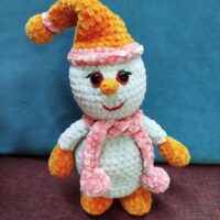 Описание товара: вязаный плюшевый снеговик амигуруми Подарите себе или близким частичку зимней сказки с этим очаровательным вязаным снеговиком, выполненным в технике амигуруми! Ручная работа и внимание к деталям делают эту игрушку по-настоящему уникальной. Особенности: Материал: мягкая плюшевая пряжа, приятная на ощупь, гипоаллергенная. Дизайн: белоснежное туловище и голова создают образ классического снеговика; яркий оранжевый колпак с розовой окантовкой добавляет игривости; морковный нос оранжевого цвета — узнаваемый элемент образа; выразительные глазки с блеском, создающие «живой» взгляд; весёлая красная улыбка придаёт игрушке дружелюбный вид; розовый шарф с объёмными помпонами — стильный акцент; оранжевые «рукавички» и «сапожки» гармонично дополняют образ. Размер: компактный, удобно держать в руках (точный размер уточняйте при заказе). Наполнитель: безопасный синтепух, обеспечивающий мягкость и упругость. Безопасность: все элементы надёжно закреплены, изделие абсолютно безопасно для детей. Преимущества: Ручная работа: каждая игрушка уникальна, с небольшими отличиями в деталях вязки. Экологичные материалы: не вызывают аллергии, подходят даже для самых маленьких. Долговечность: пряжа устойчива к износу, игрушка сохраняет форму и цвет долгое время. Универсальность: подойдёт как для игр, так и для украшения интерьера в зимний период или на Новый год. Яркий дизайн: поднимет настроение и станет любимым другом ребёнка или милым сувениром для взрослых. Рекомендации по уходу: бережная ручная стирка в прохладной воде; избегать использования агрессивных моющих средств; сушить в расправленном виде вдали от прямых солнечных лучей. Этот вязаный снеговик принесёт в дом атмосферу уюта и праздника. Отличный выбор для подарка на Новый год, Рождество или просто для создания зимнего настроения!