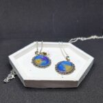 Кулоны «Звёздный шёпот» — эхо древних созвездий Перед вами не просто украшения, а магические реликвии, рождённые на стыке реальности и волшебства. Эти кулоны словно хранят в себе отблески далёких галактик, где звёзды сплетают свои истории в танце вечности. Каждый кулон обрамлён изящной металлической оправой в цвете серебра, напоминающей древние эльфийские узоры — будто искусные мастера зачаровали металл, чтобы он навеки хранил тайну небес. В центре — переливающийся состав, сотканный из оттенков ночного неба: глубокий синий плавно переходит в золотисто-жёлтый, словно рассвет, пробивающийся сквозь звёздную пыль. Маленькие искорки-звёзды, вкраплённые в состав, будто застыли в мгновении волшебства. Говорят, что каждая из них — это душа упавшей звезды, заключённая в амулет для защиты владельца. Эти звёзды шепчут древние заклинания, оберегая от бед и наполняя сердце вдохновением. Легенда гласит: тот, кто носит такой кулон, может услышать шёпот созвездий в тишине ночи. Они расскажут о забытых мирах, древних пророчествах и тайных тропах между измерениями. А если загадать желание под полной луной, держа кулон в ладони, оно непременно сбудется — ведь магия звёзд не знает преград. Позвольте этим кулонам стать вашими верными спутниками в путешествии по миру грёз и приключений. Они не просто украсят ваш образ — они станут частью вашей истории, наполняя каждый день магией и загадкой.