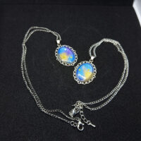 Кулоны «Звёздный шёпот» — эхо древних созвездий Перед вами не просто украшения, а магические реликвии, рождённые на стыке реальности и волшебства. Эти кулоны словно хранят в себе отблески далёких галактик, где звёзды сплетают свои истории в танце вечности. Каждый кулон обрамлён изящной металлической оправой в цвете серебра, напоминающей древние эльфийские узоры — будто искусные мастера зачаровали металл, чтобы он навеки хранил тайну небес. В центре — переливающийся состав, сотканный из оттенков ночного неба: глубокий синий плавно переходит в золотисто-жёлтый, словно рассвет, пробивающийся сквозь звёздную пыль. Маленькие искорки-звёзды, вкраплённые в состав, будто застыли в мгновении волшебства. Говорят, что каждая из них — это душа упавшей звезды, заключённая в амулет для защиты владельца. Эти звёзды шепчут древние заклинания, оберегая от бед и наполняя сердце вдохновением. Легенда гласит: тот, кто носит такой кулон, может услышать шёпот созвездий в тишине ночи. Они расскажут о забытых мирах, древних пророчествах и тайных тропах между измерениями. А если загадать желание под полной луной, держа кулон в ладони, оно непременно сбудется — ведь магия звёзд не знает преград. Позвольте этим кулонам стать вашими верными спутниками в путешествии по миру грёз и приключений. Они не просто украсят ваш образ — они станут частью вашей истории, наполняя каждый день магией и загадкой.