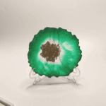 Подставки-жеоды: осколки древних миров в вашем доме Перед вами — не просто подставки под чашки, а фрагменты магических кристаллов, извлечённых из недр зачарованных земель. Словно срезы древних жеод, они хранят в себе энергию стихий и шёпот забытых заклинаний. Фиолетовая жеода: * окутана аурой мистической ночи; * мерцает, будто звёздное небо в полнолуние; * серебристое ядро в центре — это запечатанный портал в иные измерения; * её энергия помогает сосредоточиться и найти ответы на самые сложные вопросы. Зелёная жеода с золотым сердцем: * наполнена силой природы и древних лесов; * зелёный оттенок напоминает о магии друидов и целебных травах; * золотое ядро — словно солнце, заключённое в камне, приносит удачу и процветание; * создаёт атмосферу гармонии и умиротворения. Эти артефакты созданы из особой смолы, пропитанной эссенцией лунного света и солнечных лучей. Их неровные края — не случайность, а отпечаток прикосновения древних духов-хранителей. Почему эти подставки особенные? * Магическая эстетика: превратят любую сервировку в сцену из фэнтези-романа. * Практичность: защитят стол от горячих чашек и случайных царапин. * Уникальность: каждая подставка неповторима, как отпечаток пальца мага. * Энергетика: по легенде, такие жеоды усиливают интуицию и открывают каналы для вдохновения. Позвольте этим осколкам волшебства стать частью вашего быта. Пусть каждый глоток чая или кофе будет сопровождаться ощущением прикосновения к тайнам вселенной!