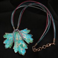 Изумительное колье, центральным элементом которого служит лист смородины, выполненный с помощью техники гальванопластика. Этот лист — не просто украшение, а маленькое произведение искусства: с одной стороны он играет зелёно-синими оттенками, словно отражая прохладу утренней росы, а с другой переливается нежно-зелёными и бирюзовыми тонами, напоминая о безмятежности летнего дня.