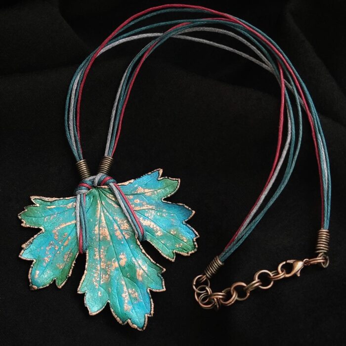 Изумительное колье, центральным элементом которого служит лист смородины, выполненный с помощью техники гальванопластика. Этот лист — не просто украшение, а маленькое произведение искусства: с одной стороны он играет зелёно-синими оттенками, словно отражая прохладу утренней росы, а с другой переливается нежно-зелёными и бирюзовыми тонами, напоминая о безмятежности летнего дня.