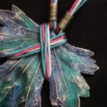 Изумительное колье, центральным элементом которого служит лист смородины, выполненный с помощью техники гальванопластика. Этот лист — не просто украшение, а маленькое произведение искусства: с одной стороны он играет зелёно-синими оттенками, словно отражая прохладу утренней росы, а с другой переливается нежно-зелёными и бирюзовыми тонами, напоминая о безмятежности летнего дня.