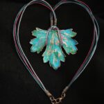 Изумительное колье, центральным элементом которого служит лист смородины, выполненный с помощью техники гальванопластика. Этот лист — не просто украшение, а маленькое произведение искусства: с одной стороны он играет зелёно-синими оттенками, словно отражая прохладу утренней росы, а с другой переливается нежно-зелёными и бирюзовыми тонами, напоминая о безмятежности летнего дня.