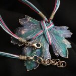 Изумительное колье, центральным элементом которого служит лист смородины, выполненный с помощью техники гальванопластика. Этот лист — не просто украшение, а маленькое произведение искусства: с одной стороны он играет зелёно-синими оттенками, словно отражая прохладу утренней росы, а с другой переливается нежно-зелёными и бирюзовыми тонами, напоминая о безмятежности летнего дня.