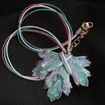 Изумительное колье, центральным элементом которого служит лист смородины, выполненный с помощью техники гальванопластика. Этот лист — не просто украшение, а маленькое произведение искусства: с одной стороны он играет зелёно-синими оттенками, словно отражая прохладу утренней росы, а с другой переливается нежно-зелёными и бирюзовыми тонами, напоминая о безмятежности летнего дня.
