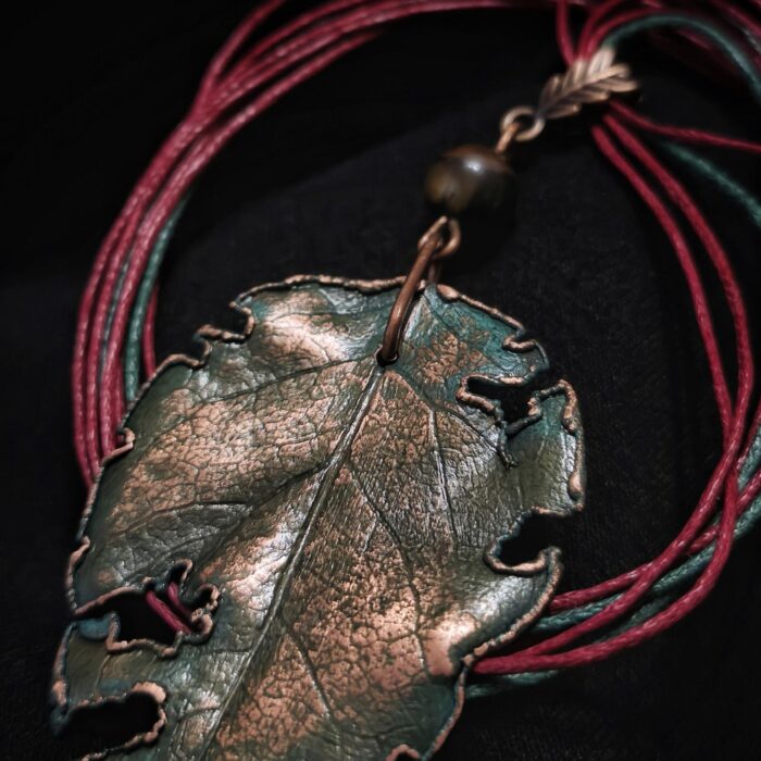 Завораживающее колье, в центре которого — подвеска в виде листа сирени, созданная с помощью техники гальванопластика. Лист словно хранит в себе историю: фактурные прожилки рассказывают о его жизни, а неровные, «объеденные» гусеницами края придают украшению особую, дикую прелесть, будто он только что был сорван в заросшем саду.