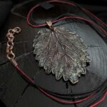 Изысканное колье, центральным элементом которого служит лист куста Яснотки, выполненный в технике гальванопластика. Поверхность листа переливается оттенками коричневого, медного и тёмно-шоколадного, а сияющая патина в зелёных тонах придаёт украшению загадочность и глубину.