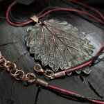 Изысканное колье, центральным элементом которого служит лист куста Яснотки, выполненный в технике гальванопластика. Поверхность листа переливается оттенками коричневого, медного и тёмно-шоколадного, а сияющая патина в зелёных тонах придаёт украшению загадочность и глубину.