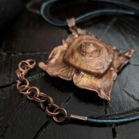 Уникальное колье, выполненное в технике гальванопластика — его центральным элементом стал хвостик от хурмы, превращённый в произведение искусства. Тёплые оттенки коричневого, медного и шоколадного окутывают подвеску, создавая ощущение природной гармонии и уюта.