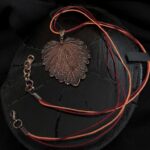 Изысканное колье, центральным элементом которого служит лист яснотки, виртуозно воссозданный в технике гальванопластика. Поверхность листа играет оттенками коричневого, медного и тёмно-шоколадного, создавая ощущение глубины и природной теплоты.