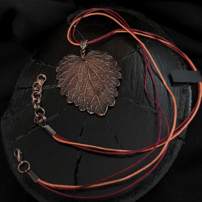 Изысканное колье, центральным элементом которого служит лист яснотки, виртуозно воссозданный в технике гальванопластика. Поверхность листа играет оттенками коричневого, медного и тёмно-шоколадного, создавая ощущение глубины и природной теплоты.