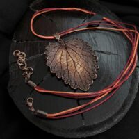 Изысканное колье, центральным элементом которого служит лист яснотки, виртуозно воссозданный в технике гальванопластика. Поверхность листа играет оттенками коричневого, медного и тёмно-шоколадного, создавая ощущение глубины и природной теплоты.