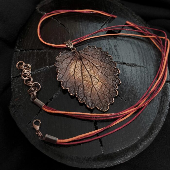 Изысканное колье, центральным элементом которого служит лист яснотки, виртуозно воссозданный в технике гальванопластика. Поверхность листа играет оттенками коричневого, медного и тёмно-шоколадного, создавая ощущение глубины и природной теплоты.