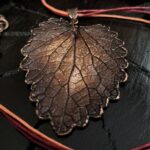 Изысканное колье, центральным элементом которого служит лист яснотки, виртуозно воссозданный в технике гальванопластика. Поверхность листа играет оттенками коричневого, медного и тёмно-шоколадного, создавая ощущение глубины и природной теплоты.