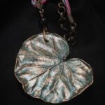 Изысканное колье, в центре которого — подвеска в виде листа скумпии, редкого растения-эндемика, произрастающего в Крыму. Лист, выполненный с помощью техники гальванопластика, поражает своей реалистичностью: каждая фактурная прожилка словно хранит в себе дыхание природы, её незримую энергию.