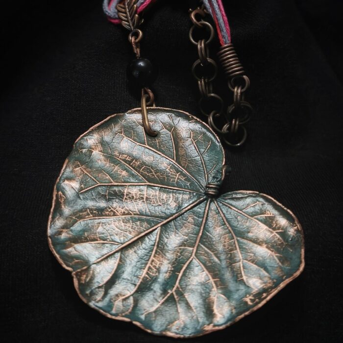 Изысканное колье, в центре которого — подвеска в виде листа скумпии, редкого растения-эндемика, произрастающего в Крыму. Лист, выполненный с помощью техники гальванопластика, поражает своей реалистичностью: каждая фактурная прожилка словно хранит в себе дыхание природы, её незримую энергию.