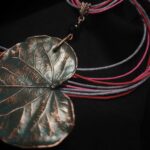 Изысканное колье, в центре которого — подвеска в виде листа скумпии, редкого растения-эндемика, произрастающего в Крыму. Лист, выполненный с помощью техники гальванопластика, поражает своей реалистичностью: каждая фактурная прожилка словно хранит в себе дыхание природы, её незримую энергию.