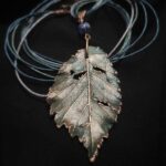 Утончённое колье, центральным элементом которого служит подвеска в виде листа Вяза, выполненная с помощью техники гальванопластика. Лист словно хранит в себе дыхание леса: его поверхность изобилует фактурными прожилками и природными дырочками, придающими украшению неповторимую естественность.