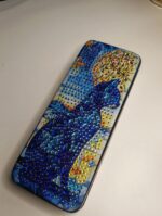 Роскошный футляр для очков, украшенный авторской алмазной вышивкой, превратит хранение аксессуаров в настоящее эстетическое удовольствие. Центральным элементом дизайна стал загадочный силуэт кошки, выполненный с использованием страз насыщенных синих, фиолетовых и бирюзовых оттенков.