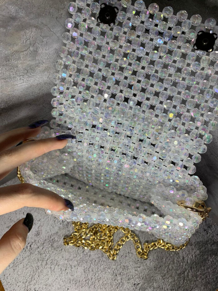 Представляем изысканную сумку из бусин, которая станет настоящим украшением вашего образа! Эта элегантная модель выполнена из прозрачных переливающихся бусин, создающих эффект мерцающего хрусталя. Благодаря тщательной ручной работе каждая бусина аккуратно закреплена, формируя цельную и прочную конструкцию.