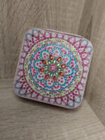 Изящная шкатулка, украшенная авторской росписью и россыпью страз, станет не только практичным предметом для хранения мелочей, но и ярким акцентом в интерьере. Центральным элементом дизайна служит узор, напоминающий мандалу: симметричный орнамент с цветочными мотивами притягивает взгляд и создаёт ощущение гармонии.