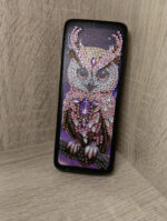 Элегантный футляр для очков, украшенный изысканной алмазной вышивкой с изображением совы, станет не только практичным аксессуаром, но и стильным элементом вашего образа. Центральным элементом дизайна является детализированное изображение совы, выполненное с использованием разноцветных страз и бусин — от нежно-розовых и перламутровых до насыщенных фиолетовых и золотистых оттенков.