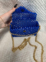 Роскошный клатч из бусин — воплощение гламура и утончённого вкуса. Эта модель выполнена в насыщенном королевском синем цвете, который притягивает взгляды и подчёркивает индивидуальность обладательницы. Корпус клатча полностью покрыт аккуратными квадратными бусинами, создающими эффект мерцающего кристалла. Благодаря ручной работе каждая деталь идеально подогнана, а поверхность выглядит безупречно.