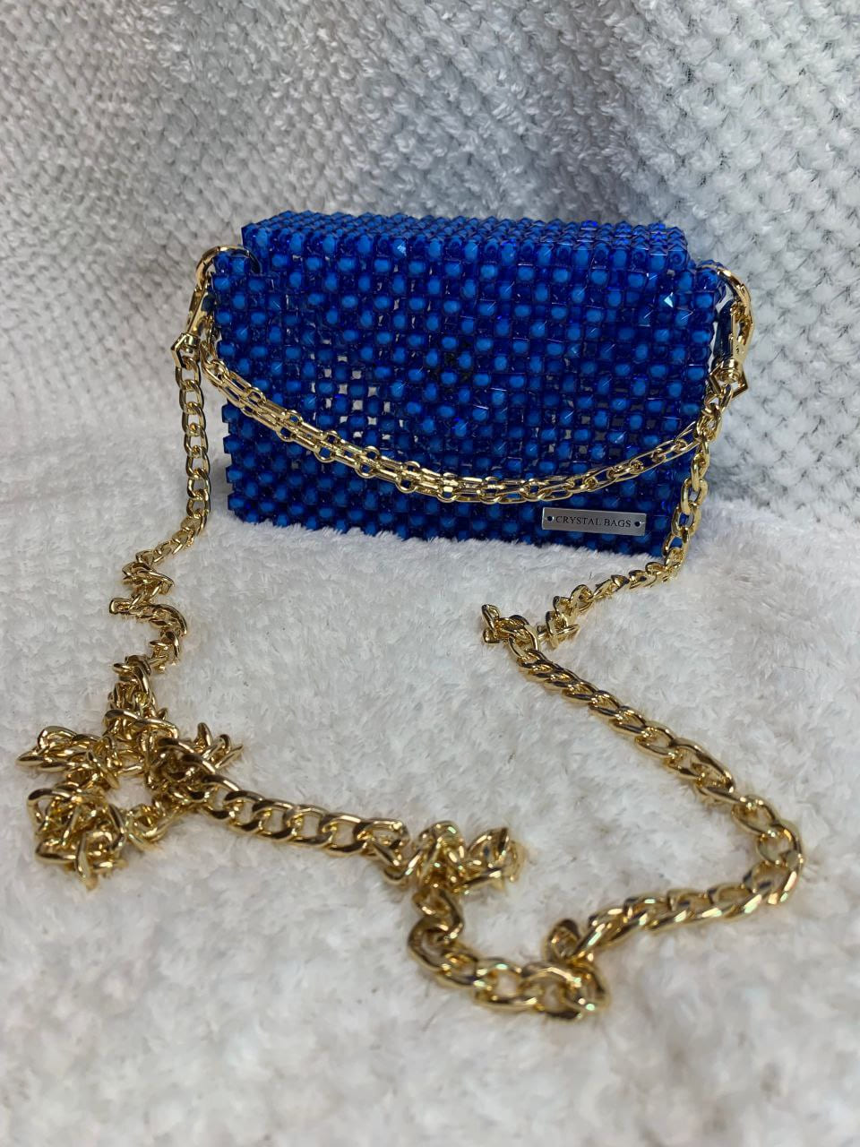 26 Роскошный клатч из бусин — воплощение гламура и утончённого вкуса. Эта модель выполнена в насыщенном королевском синем цвете, который притягивает взгляды и подчёркивает индивидуальность обладательницы. Корпус клатча полностью покрыт аккуратными квадратными бусинами, создающими эффект мерцающего кристалла. Благодаря ручной работе каждая деталь идеально подогнана, а поверхность выглядит безупречно.