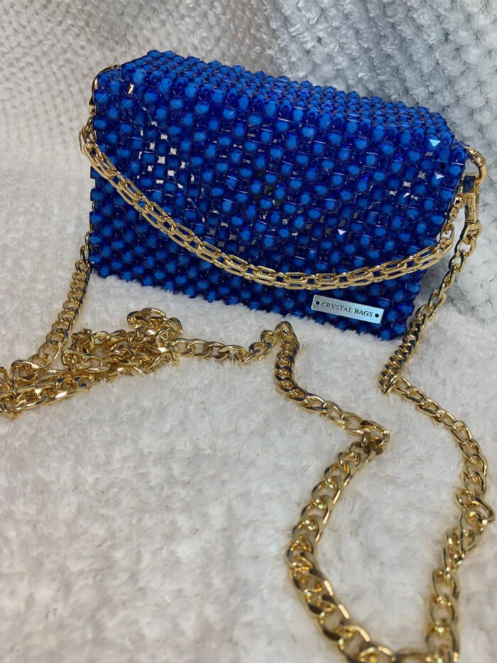 Роскошный клатч из бусин — воплощение гламура и утончённого вкуса. Эта модель выполнена в насыщенном королевском синем цвете, который притягивает взгляды и подчёркивает индивидуальность обладательницы. Корпус клатча полностью покрыт аккуратными квадратными бусинами, создающими эффект мерцающего кристалла. Благодаря ручной работе каждая деталь идеально подогнана, а поверхность выглядит безупречно.