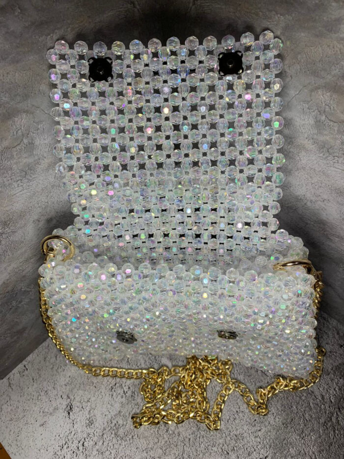 Представляем изысканную сумку из бусин, которая станет настоящим украшением вашего образа! Эта элегантная модель выполнена из прозрачных переливающихся бусин, создающих эффект мерцающего хрусталя. Благодаря тщательной ручной работе каждая бусина аккуратно закреплена, формируя цельную и прочную конструкцию.
