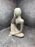 Элегантная интерьерная статуэтка, выполненная в абстрактном стиле, воплощает образ задумчивого человека, погружённого в размышления. Фигура сидит в расслабленной позе: одна рука поддерживает голову, другая естественно опущена, что создаёт ощущение глубокой задумчивости и внутреннего диалога.