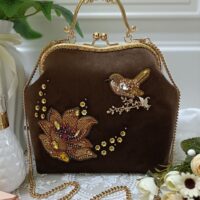 Сумочка с фермуаром "Райский сад"— воплощение элегантности и утончённости. Представляю изысканную сумочку ручной работы, которая станет жемчужиной вашего гардероба. Выполненная в благородном коричневом оттенке, она сочетает в себе роскошь классики и изящество детализированной отделки. Особенности: Материал: мягкий бархат, приятный на ощупь, создающий ощущение роскоши. Застёжка: классический фермуар с изысканной золотистой фурнитурой, придающий аксессуару винтажный шарм. Ручка: декоративная металлическая ручка с витиеватым орнаментом — акцент, подчёркивающий утончённость дизайна. Цепочка: длинная золотистая цепочка позволяет носить сумочку на плече, добавляя образу лёгкости и грации. Декор: главная изюминка — ручная вышивка с использованием бисера, пайеток и страз: - объёмный цветок в тёплых золотисто-коричневых тонах; - изящная птичка, сидящая на веточке, выполненная с особой детализацией; - россыпь мелких цветочков, создающих гармоничный узор. Размер сумочки: высота 21 см, длина по донышку 22 см, ширина 9 см. Ремень- цепочка в комплекте.